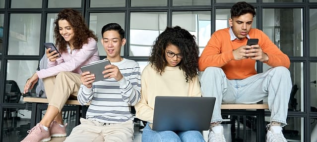 Multiracial students at high school campus using devices. Course preparation.